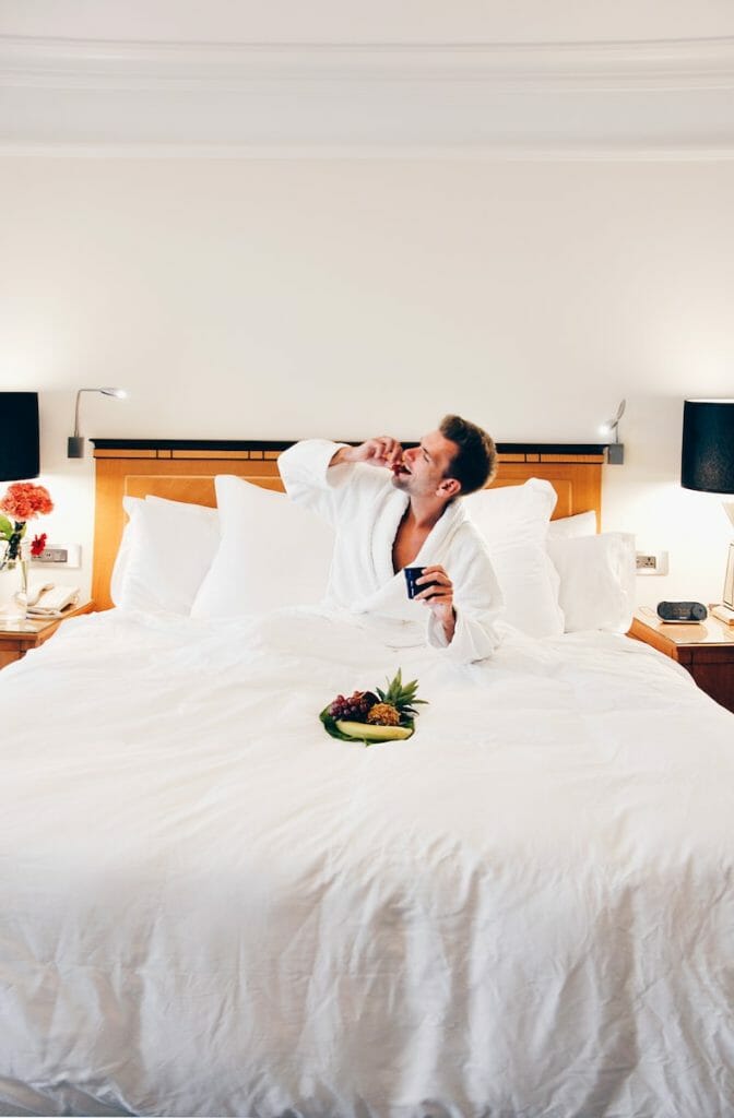man wearing bathrobe eating on bed